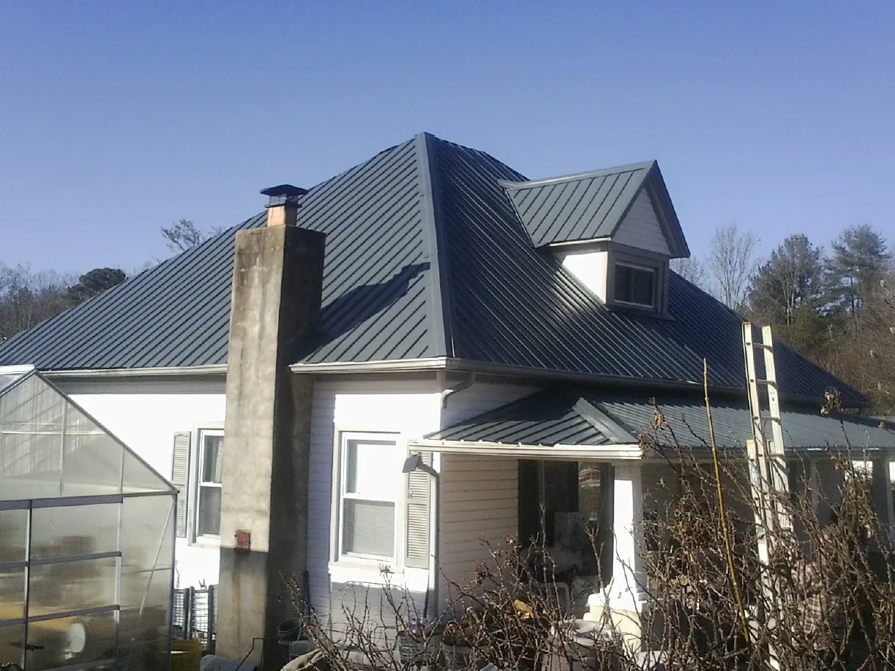 Dark blue standing seam metal roof on a white farmhouse with dormer — Slate & Tile Roof Repair by Roofing Brothers in Constantia