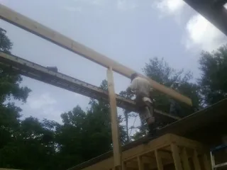 Carpenter setting a ridge beam over a new addition frame — Ice Dam Removal by Roofing Brothers in Constantia