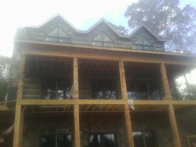 Dormers and porch framing on a large log home under construction — Roof Coating work by our crew in Constantia