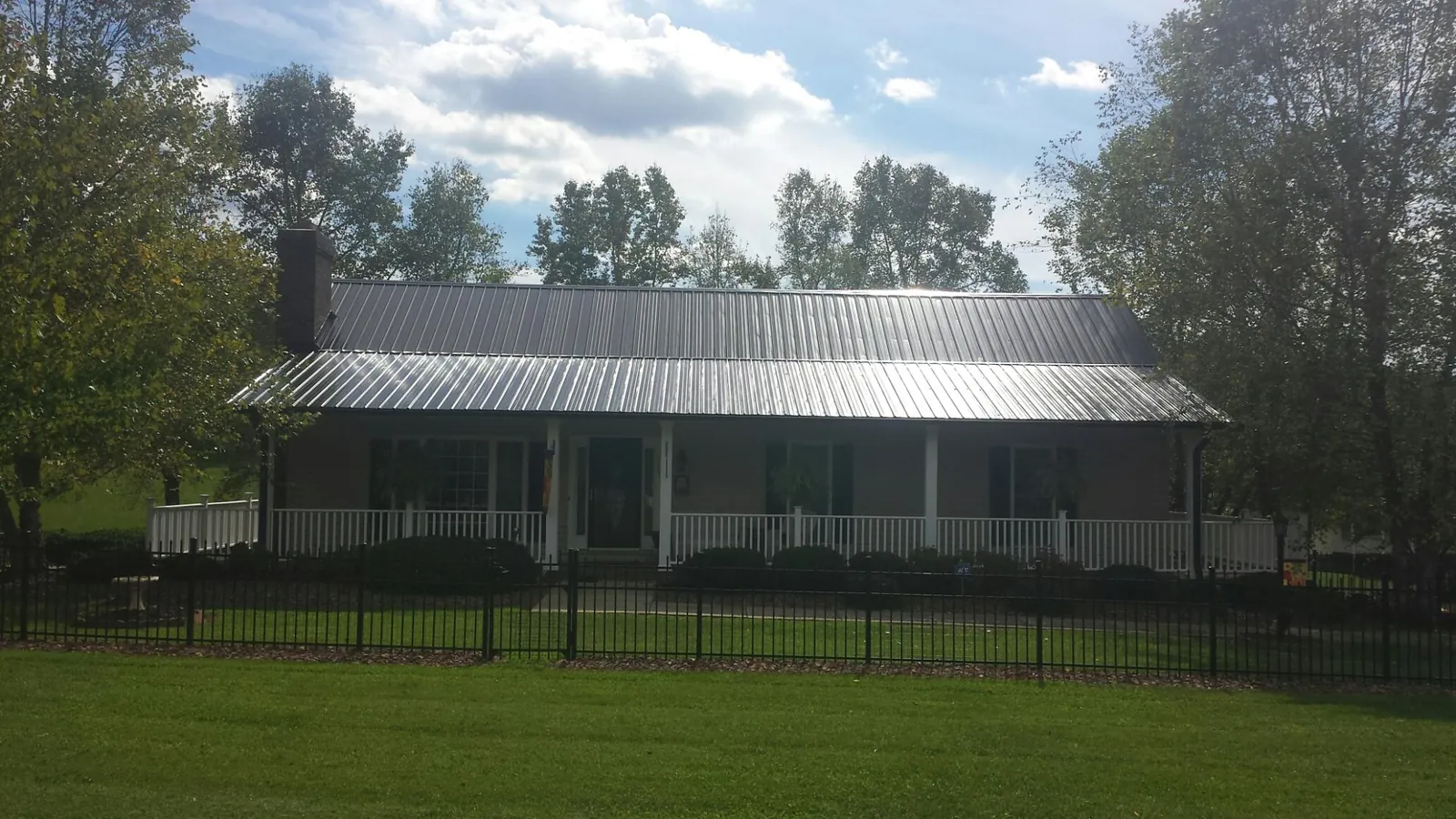 Gray metal roof on a brick ranch with a full width front porch — Gutter Guard Installation work by our crew in Constantia