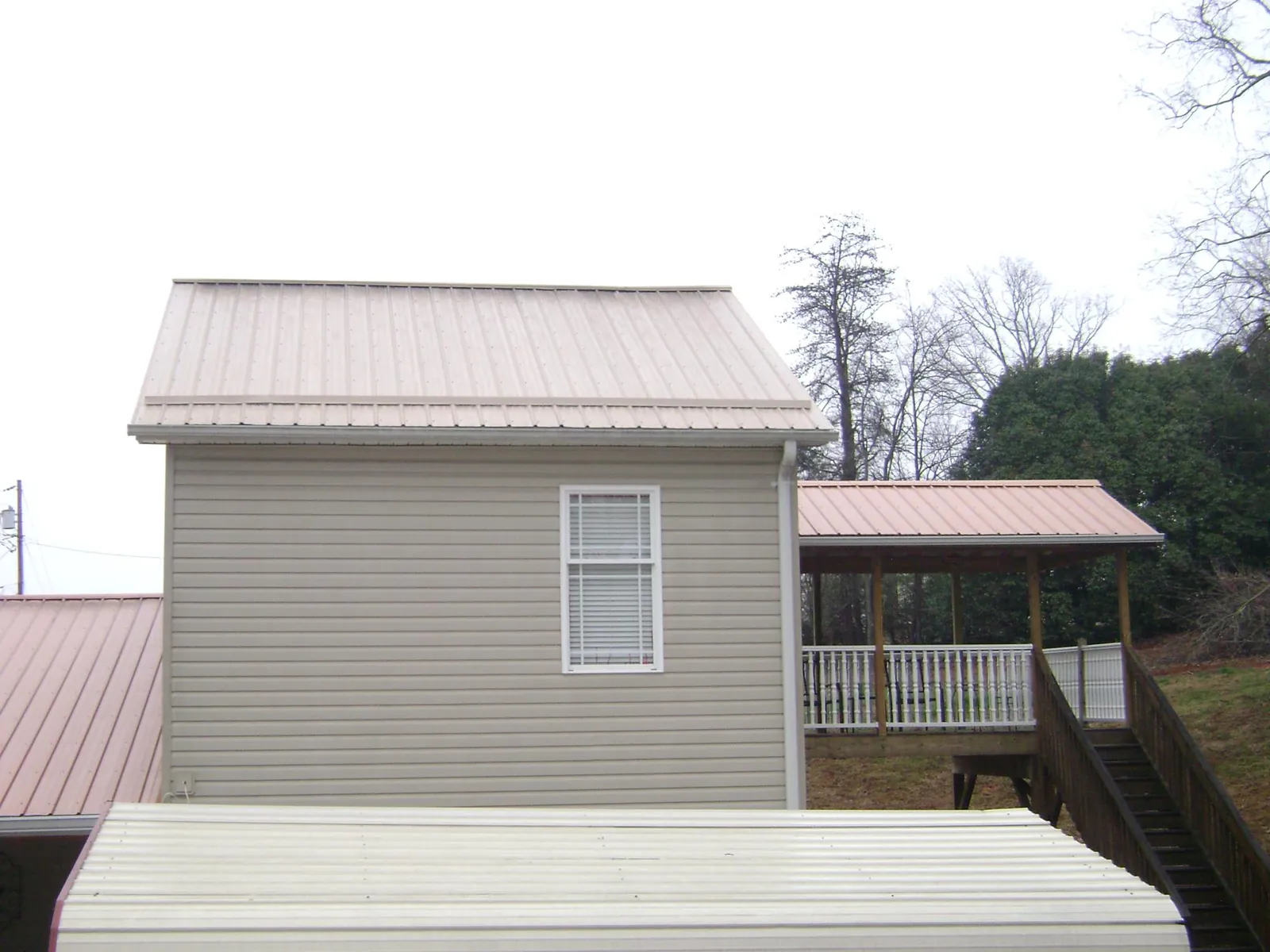Tan metal roofs on a two story addition and attached porch, from a Roof Replacement job in Constantia
